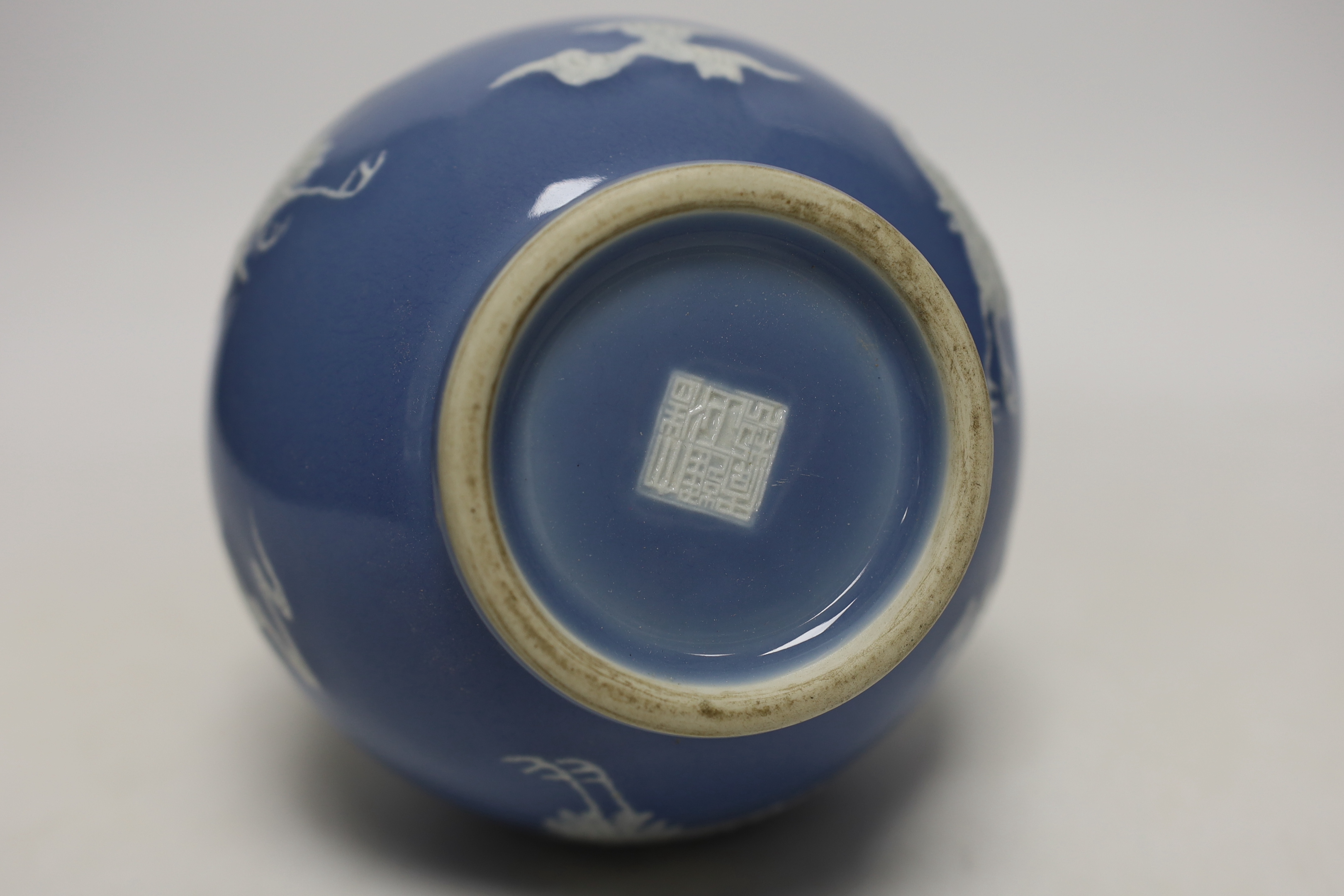 A Chinese blue bottle vase decorated in relief with cranes, on stand, 32cm high overall
